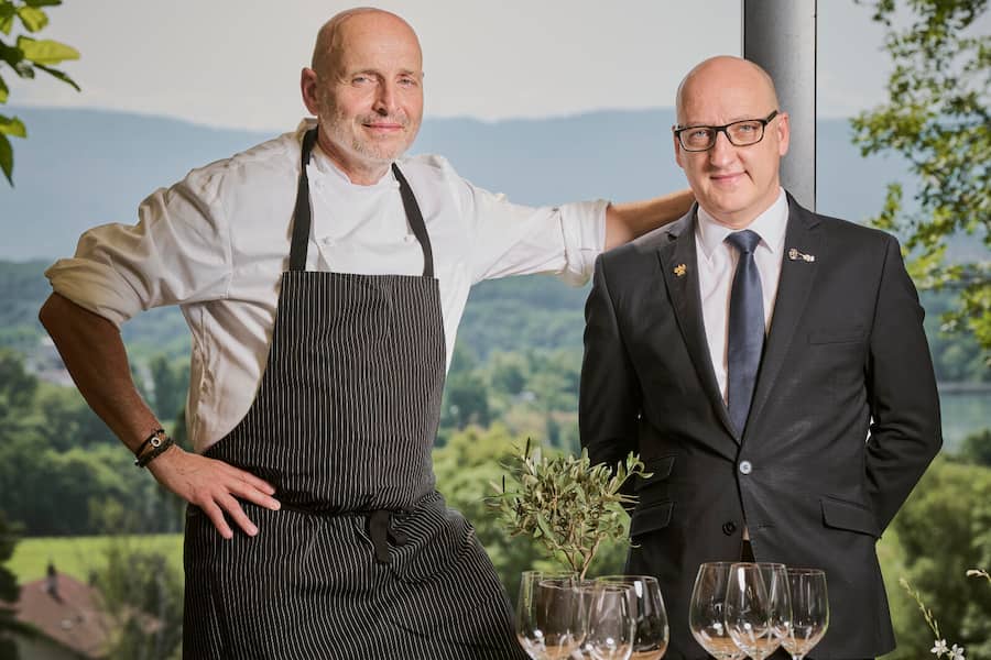 Der "Gastgeber des Jahres" 2024 Esteban Valle (rechts), posiert mit Küchenchef Philippe Chevrier (links) auf der Terrasse der Domaine Châteauvieux am Freitag, den 28. Juni 2024 in Satigny (© Gabriel Monnet).