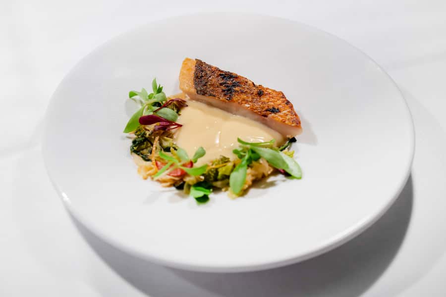 Gourmetfestival St. Moritz 2026. Behind the Scenes, 4 Hands Dinner im Grand Hotel des Bains Kempinski mit Joseph Lidgerwood aus Seoul und Marcel Ravin aus Monaco. Vorspeise von Gastkoch Joseph Lidgerwood, Roter Schnapper, Beurre Blanc-Sosse mit Huehnerfett, Gemuese aus der Region. Fotografiert am 27. August 2026