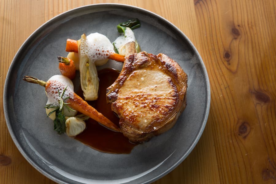 Schweinskotelette aus le Noirmont, Kartoffelstock und Frühlingsgemüse.