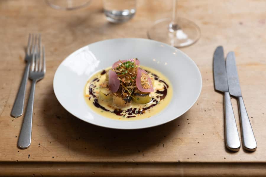Restaurant Satt Gericht: GESCHMORTER LAUCH, Rauch-Beurre Blanc, Kürbiskernöl, Baumnüsse, eingelegte rote zwiebeln.
