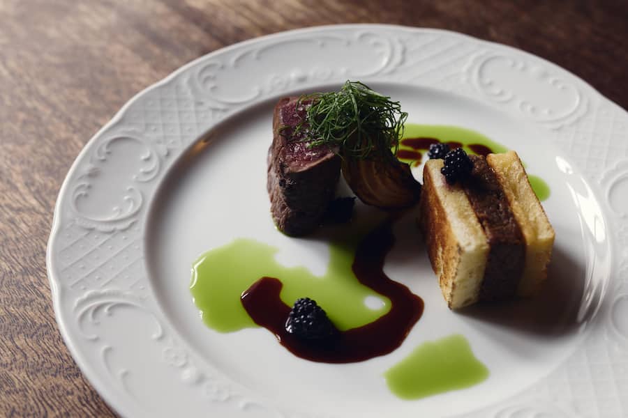 Hirsch vom Pilatus (Hirsch-Filet und Brioche gefüllt mit Hirschschulter), angebratene im Essig eingelegte Zwiebel, Sauerampfer Chiffonade, Sauerampferöl, Wildbrommbeeren aus dem Bireggwald, Wild-Jus aromatisiert mit Gin von Gutannen.