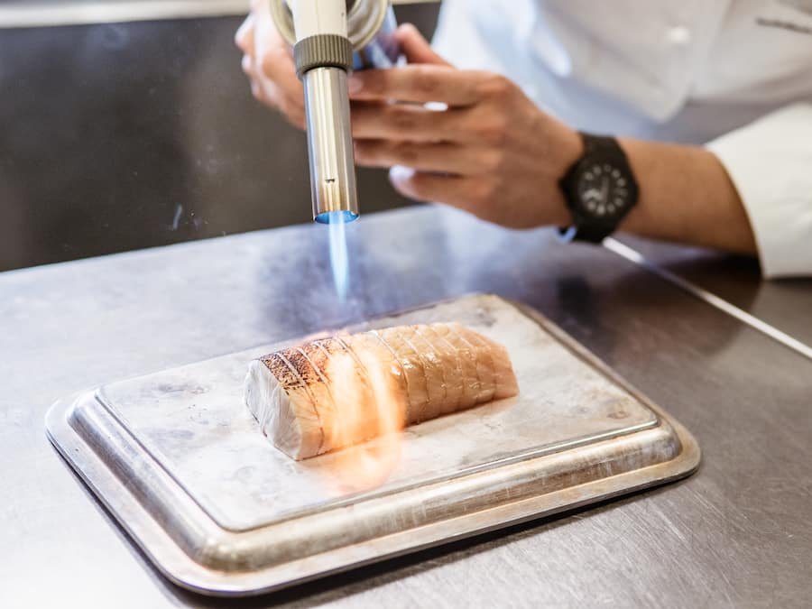 Chefkoch Rolf Fliegauf, Restaurant Ecco, Giardino Ascona - beim Fisch flämmen - 16.8.2018 - Copyright: Olivia Pulver